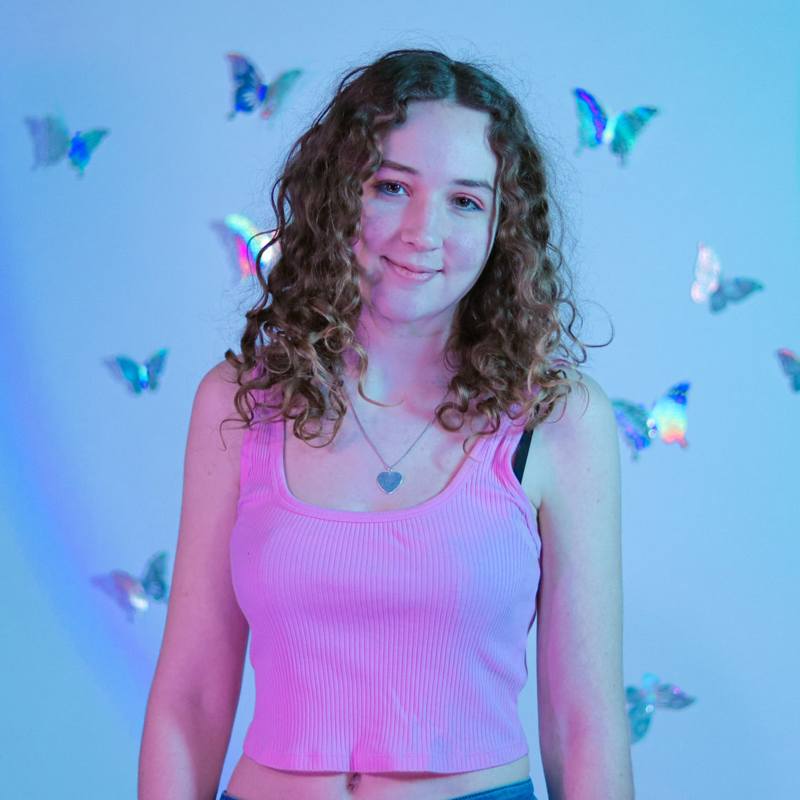 Libby stands and smiles, with silver butterflies in the background