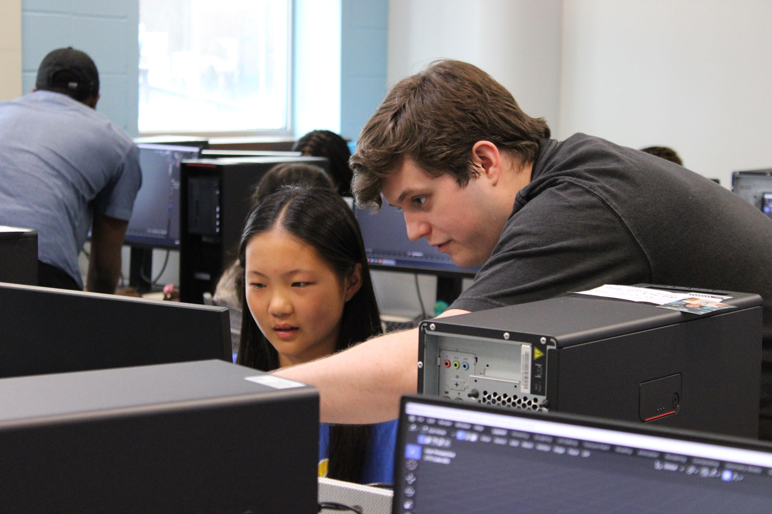 Miles and a pre-college student look at a computer monitor.