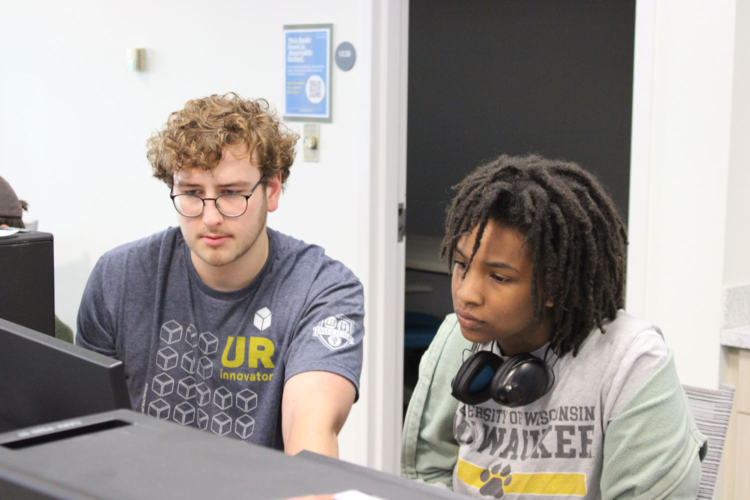 Liam helps a student with their project.