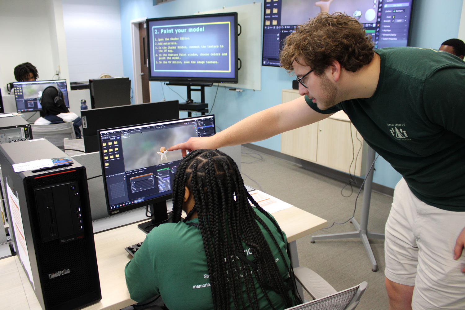 Liam points at a students 3D model created in Blender.