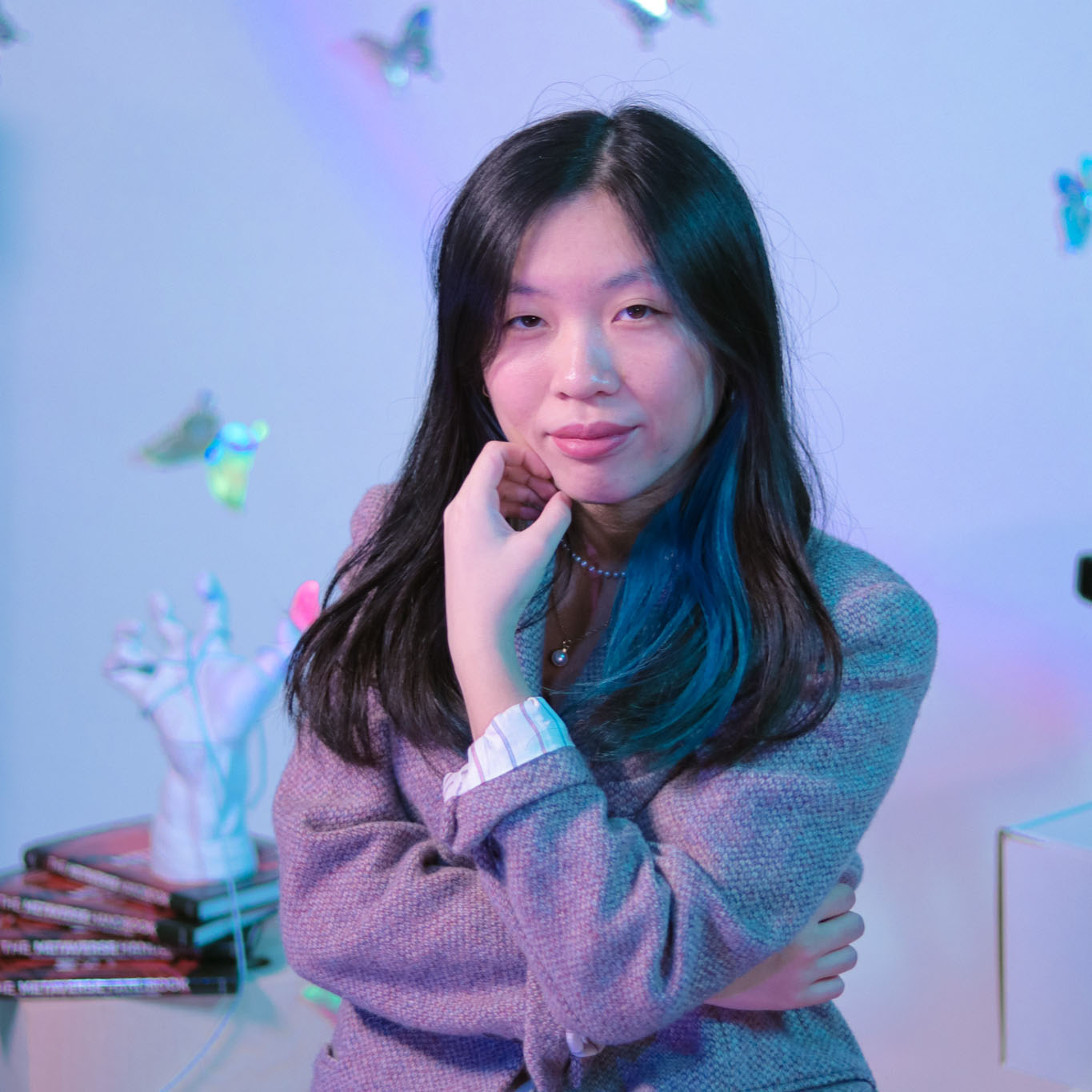 Sarah looks forward while butterflies and a hand statue adorn the background.