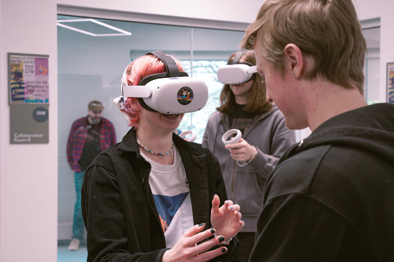 Sam helps a student with the Meta Quest 2 headset while another student uses a headset in the background.