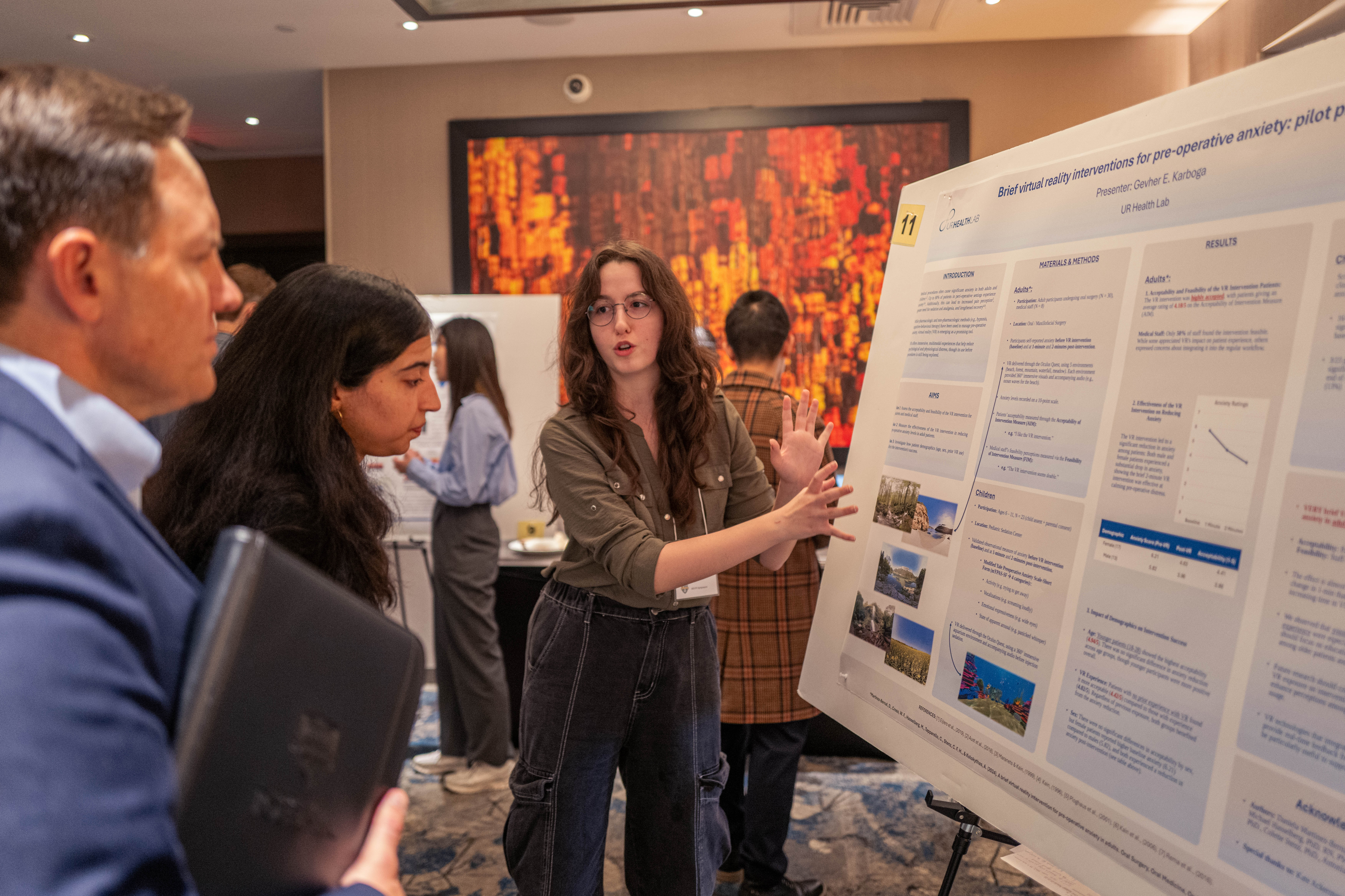 Student presents poster to visitors at AR/VR symposium.