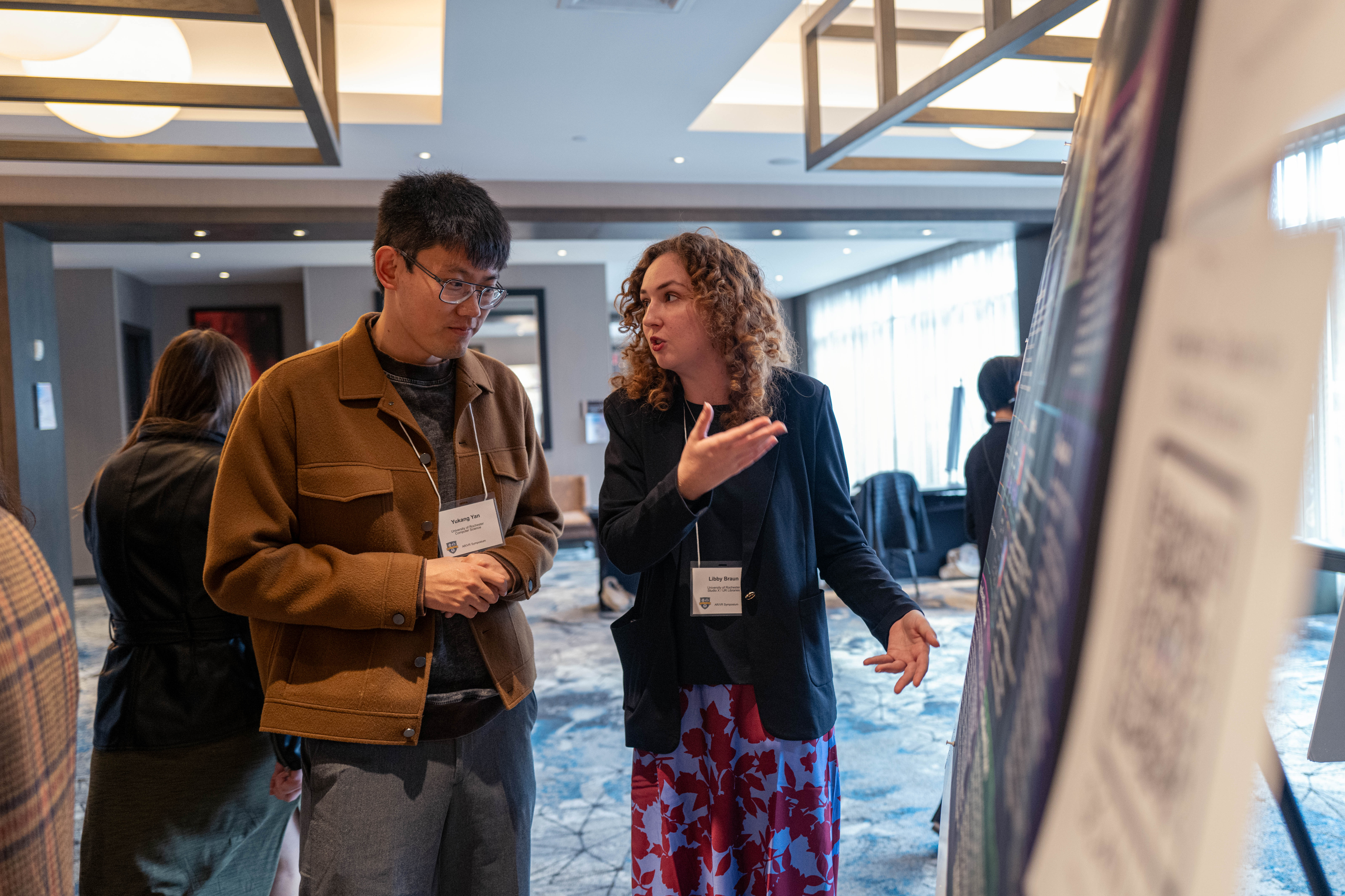 Student presents poster to visitor at AR/VR symposium.